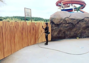 Gisa Matos working beside a wood-textured wall at a water park